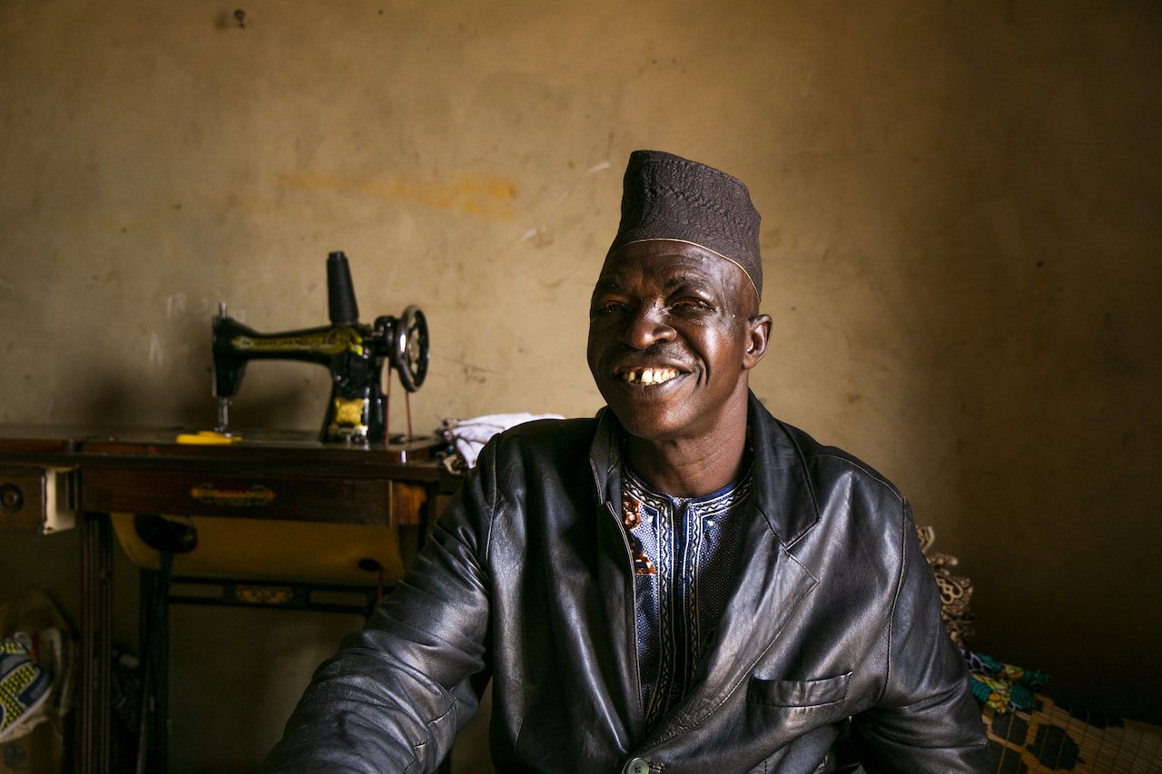 Fousseni Seko Sembere is all smiles after his surgery. Behind him is his sewing machine. A few days ago he was afraid to come to the hospital, today he can work again.