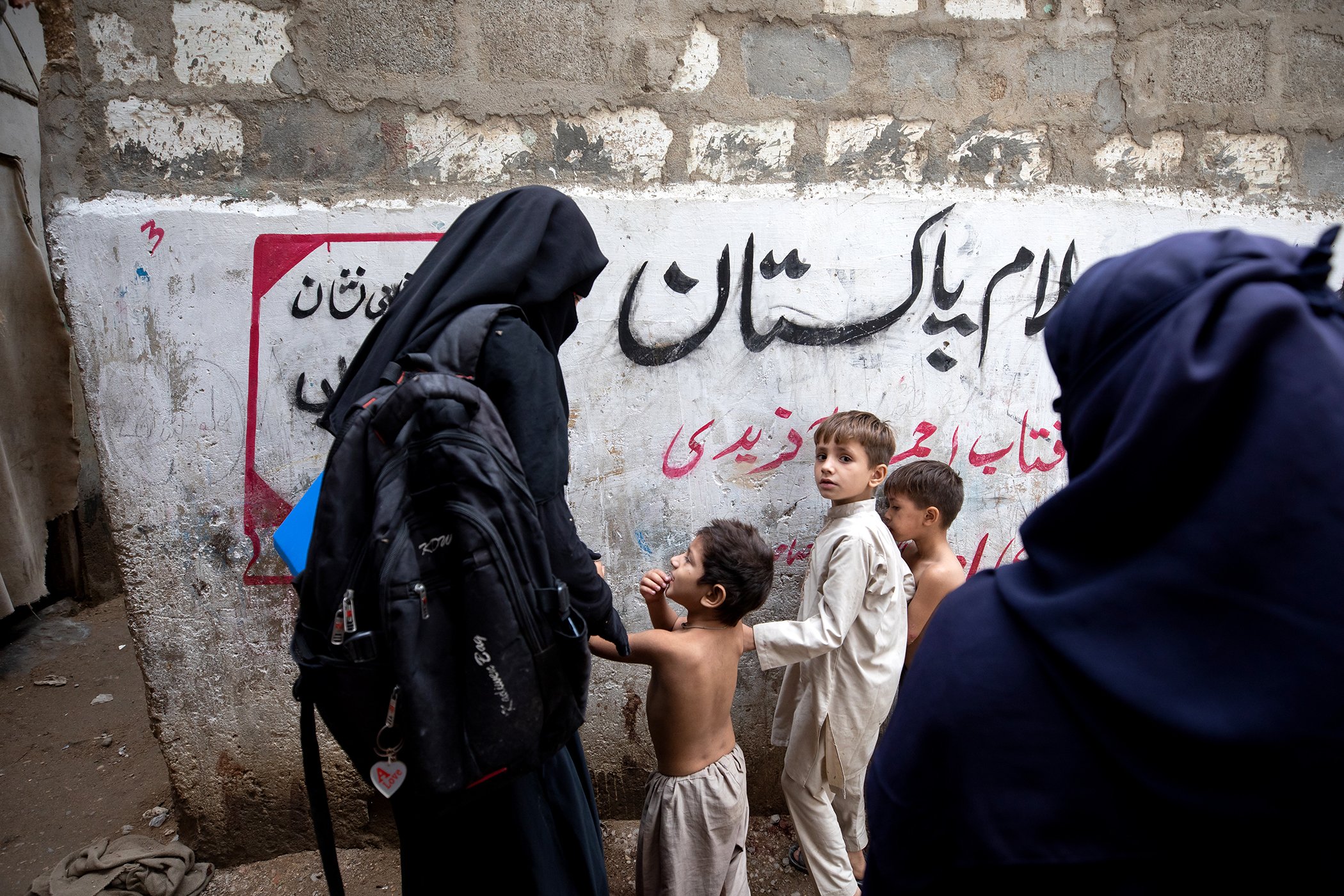 A polio vaccination team checks for vaccination markings on children's fingers as they come across them playing on the street in Sultanabad, Karachi, Pakistan on Aug. 21, 2022.