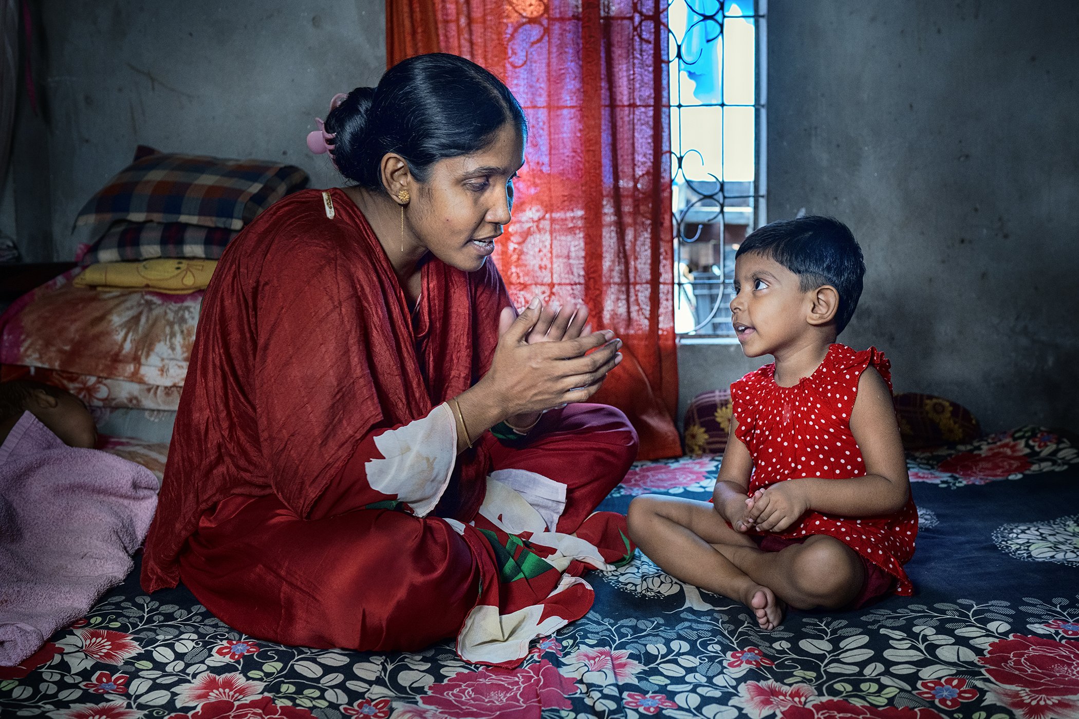 Hamida is photographed with her daughter Nusrat Jahan inside their one-bedroom house in Dhaka, Bangladesh. Without access to a child care center, it would not have been possible for Hamida to continue working in the garment factory.