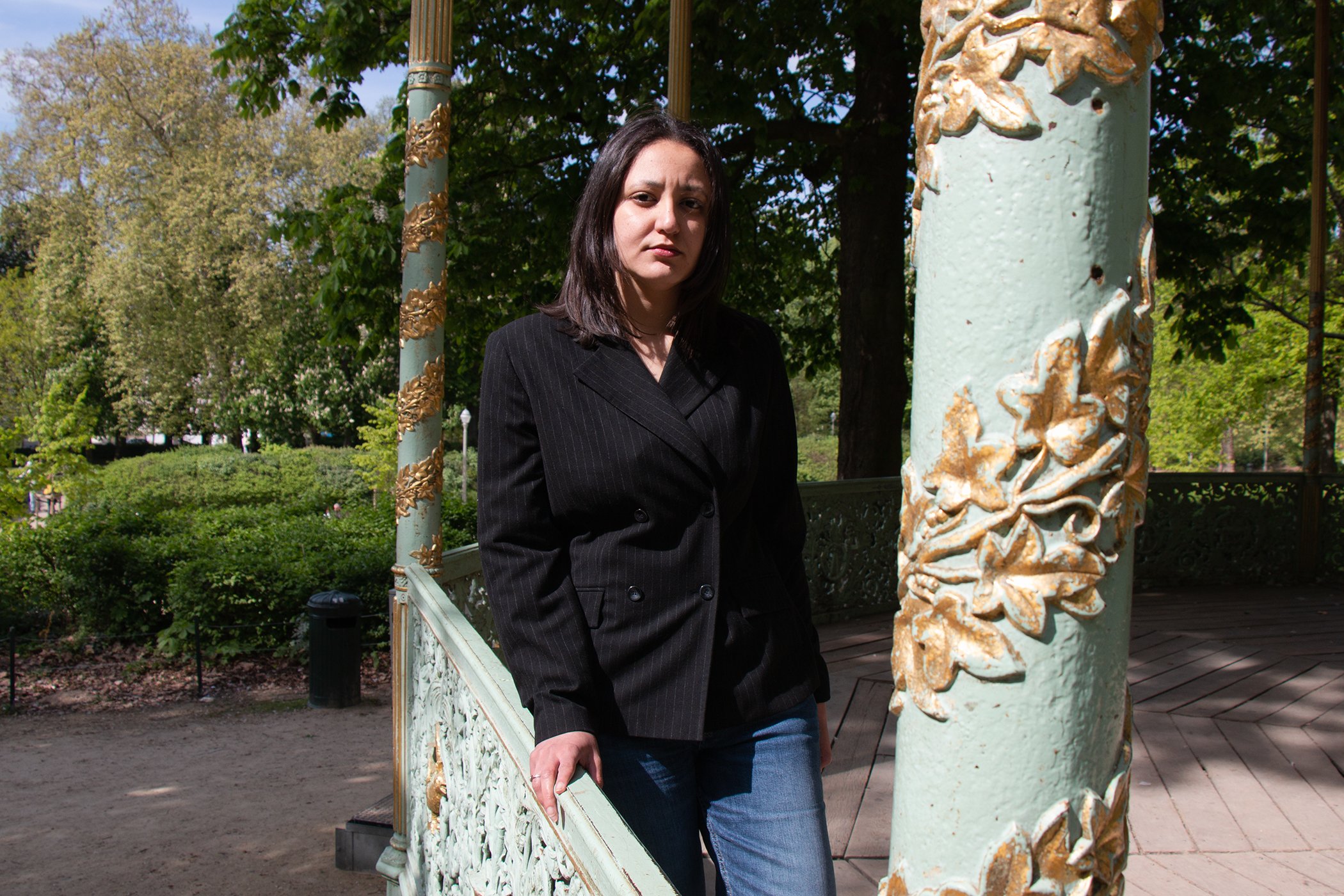 Portrait of Gehad Khaled standing under a pergola in Parc de Bruxelles, Brussels, Belgium in April 2025. Gehad Khaled shares how the imprisonment of her mother, Egyptian lawyer and human rights defender Hoda Abdelmoneim, has impacted her family.