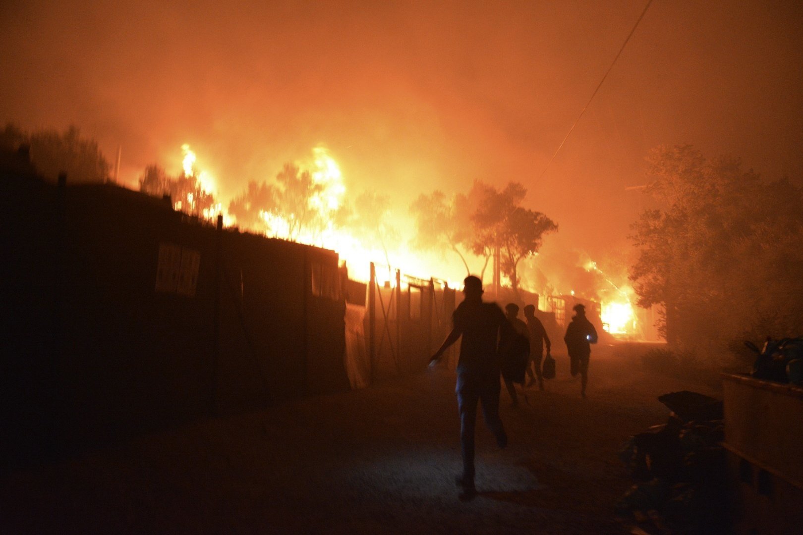 Refugees and migrants run as fire burns in the Moria refugee camp on the northeastern Aegean island of Lesbos, Greece, on Sept. 9, 2020.
