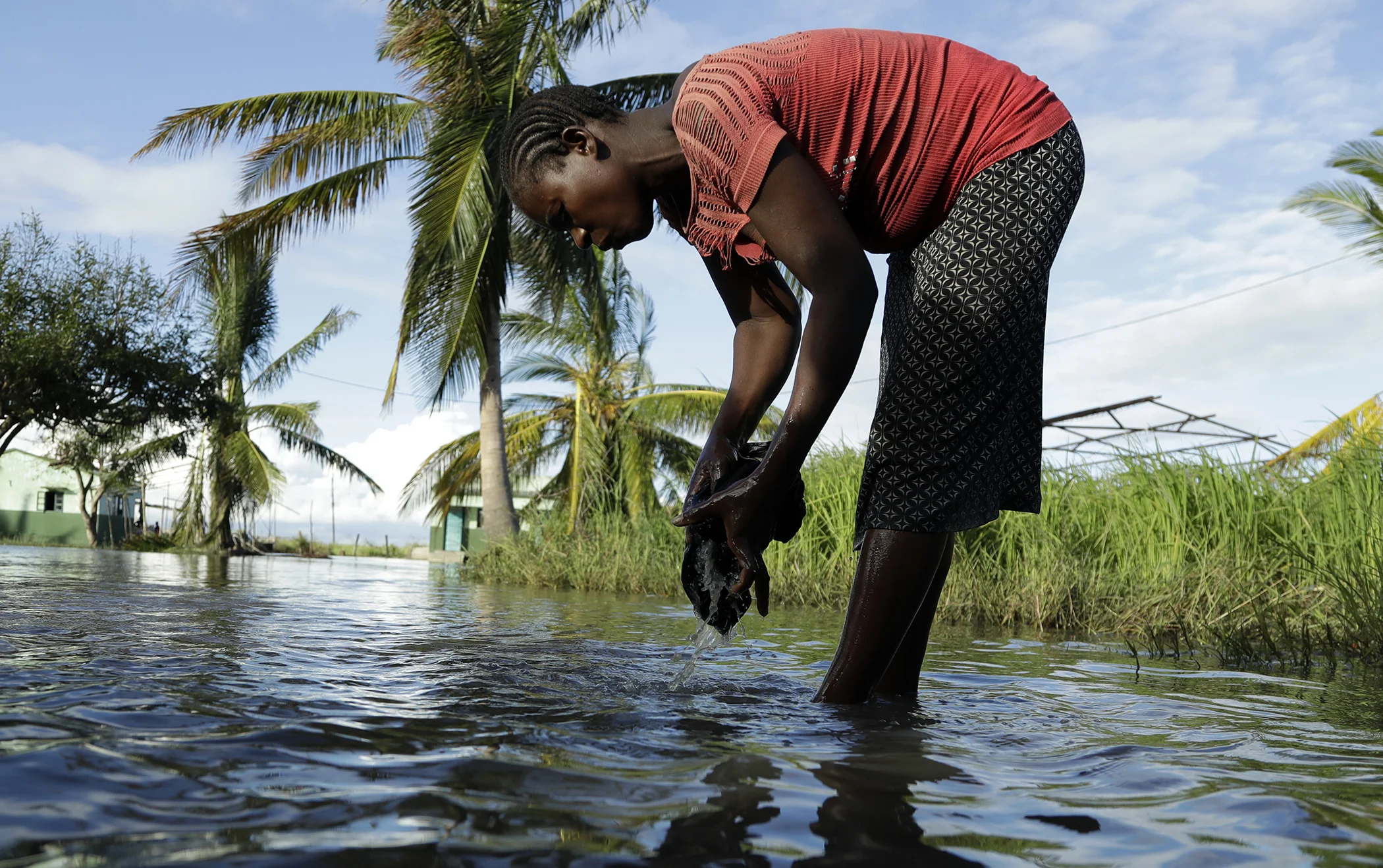 A woman washes her clothes in a flooded residential area in Nhamatanda, about 100km west of Beira, March 21, 2019. A week after Cyclone Idai lashed southern Africa, flooding still raged as torrential rains caused a dam to overflow in Zimbabwe.
